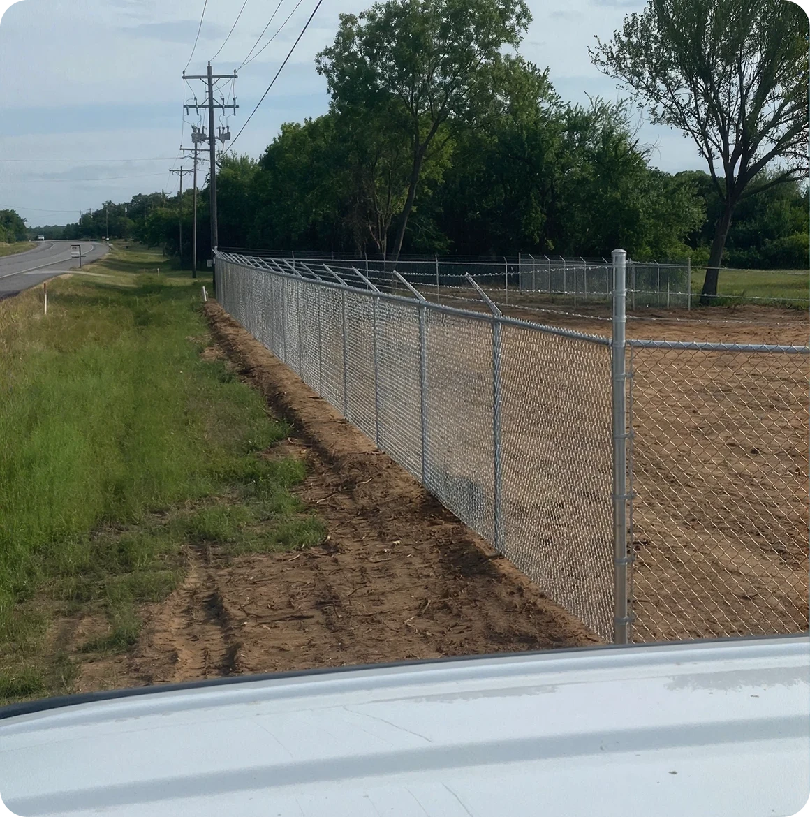 Chain-link fence by a rural road.