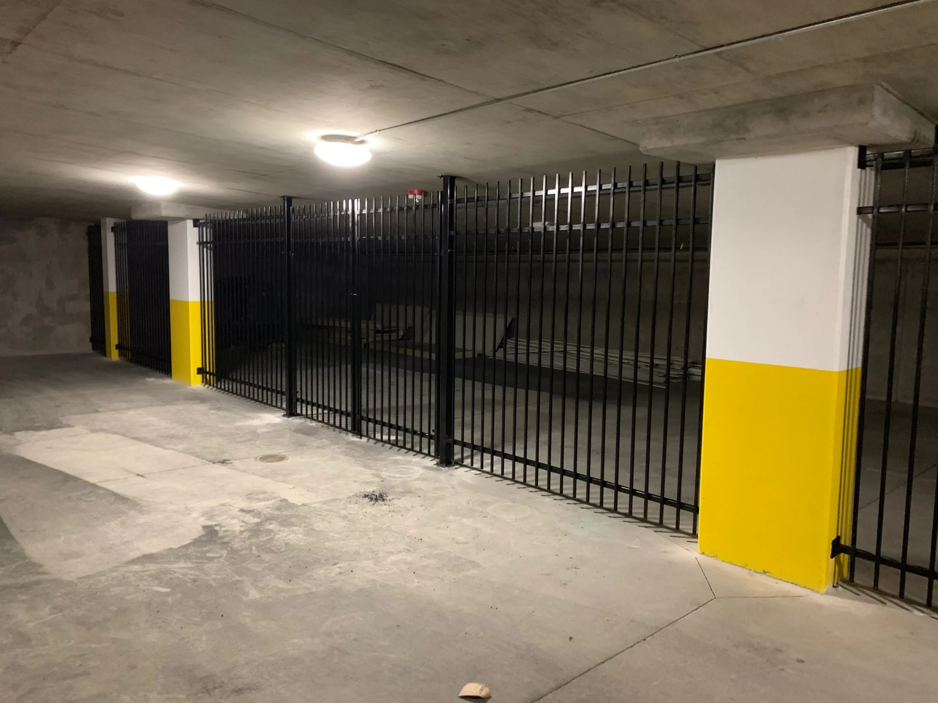 Parking garage with a black and yellow gate, a floor, walls, ceiling, and lights