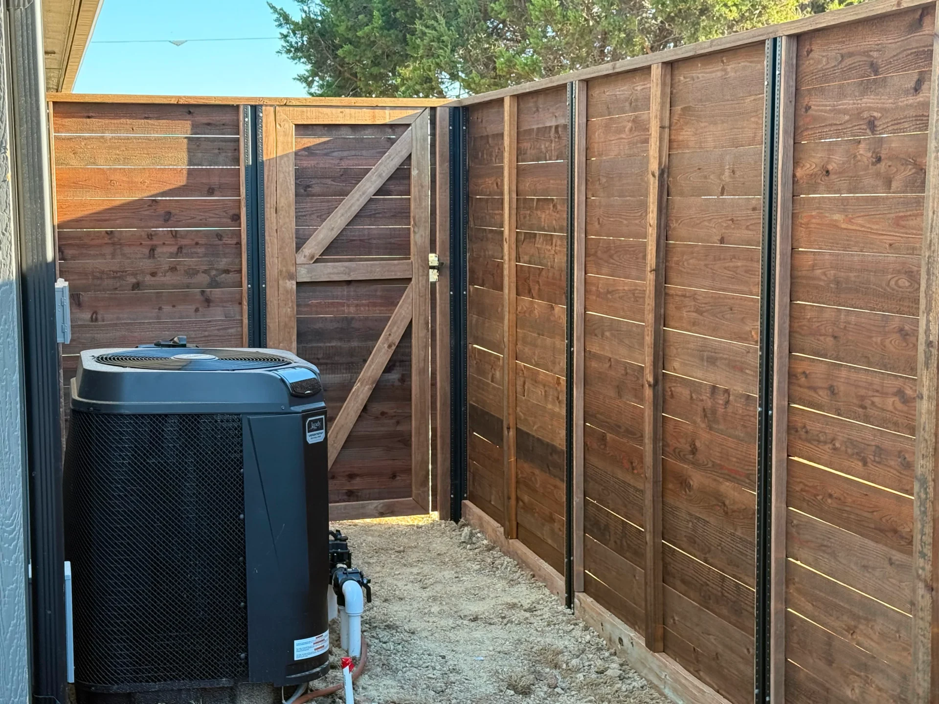 Air conditioner sitting in front of a wooden fence in a backyard in, CA